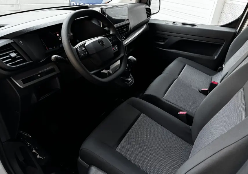 Intérieur côté conducteur du Peugeot Expert Fourgon 2025, montrant tableau de bord moderne et sièges tissu gris et noir.