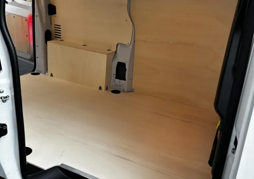 Intérieur du coffre du Peugeot Expert Fourgon blanc, vue latérale droite montrant l'aménagement bois clair et l'espace de chargement.