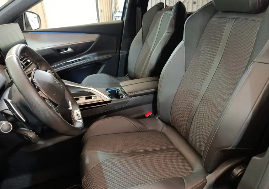 Vue intérieure côté conducteur du Peugeot 5008 2023, sièges en cuir noir et volant multifonctions en cuir.