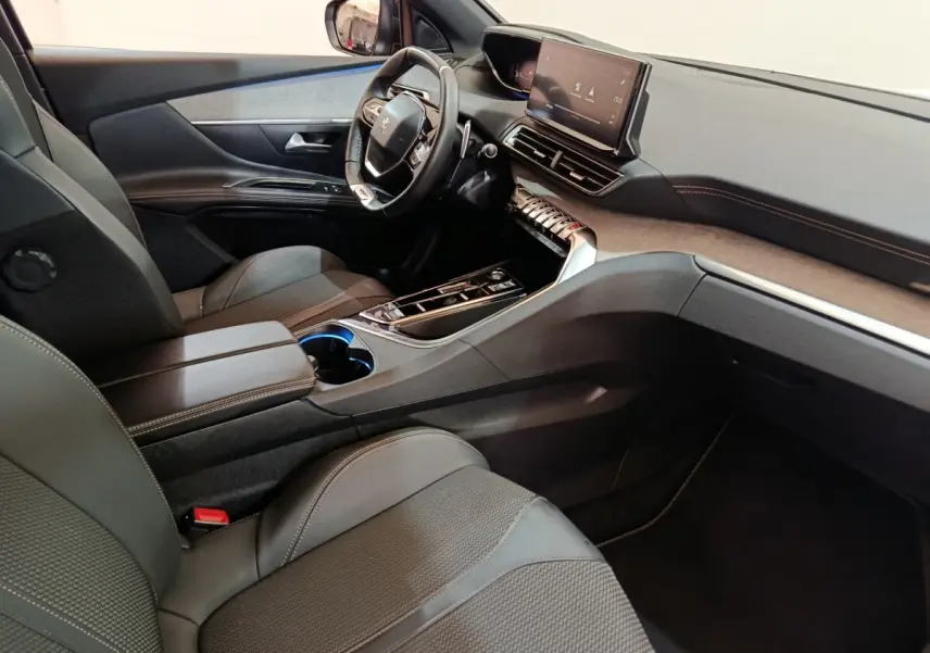 Intérieur Peugeot 5008 GT 2023 vu côté conducteur, tableau de bord moderne avec écran tactile et volant cuir noir.