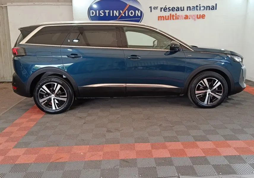 Vue de profil côté gauche d’un Peugeot 5008 GT bleu 2023 avec jantes alliage et toit noir.