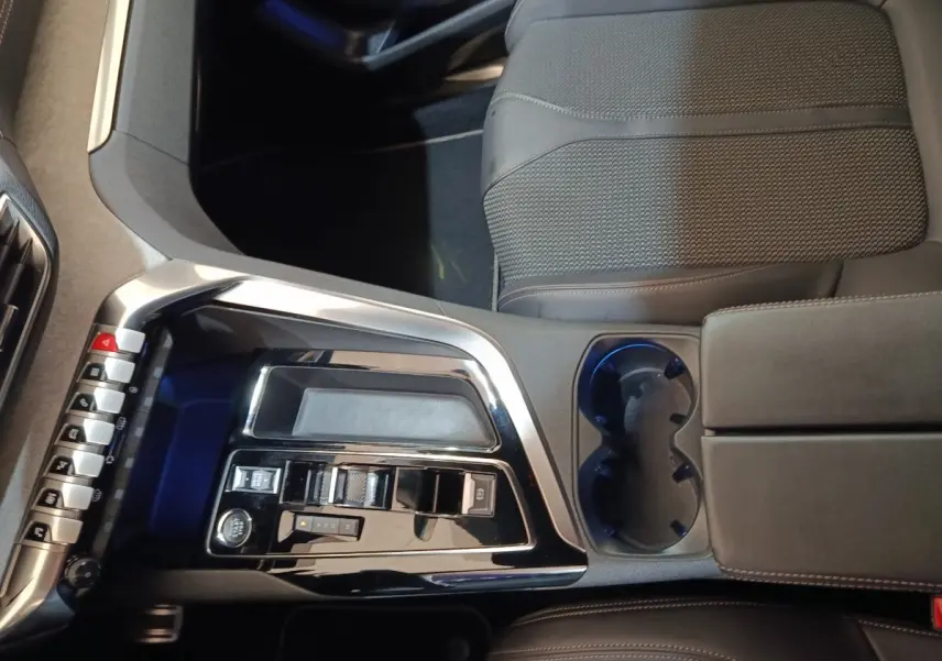 Vue intérieure centrée sur la console centrale noire brillante et les sièges en tissu gris du Peugeot 5008 GT 2023.