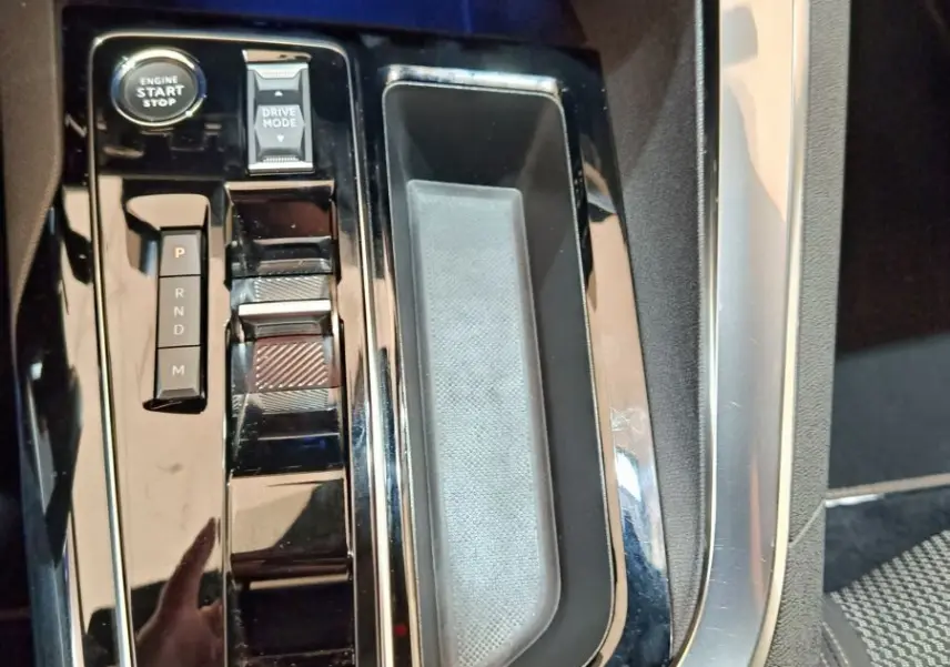 Gros plan sur la console centrale noire brillante du Peugeot 5008 avec bouton démarrage et sélecteur de mode de conduite.