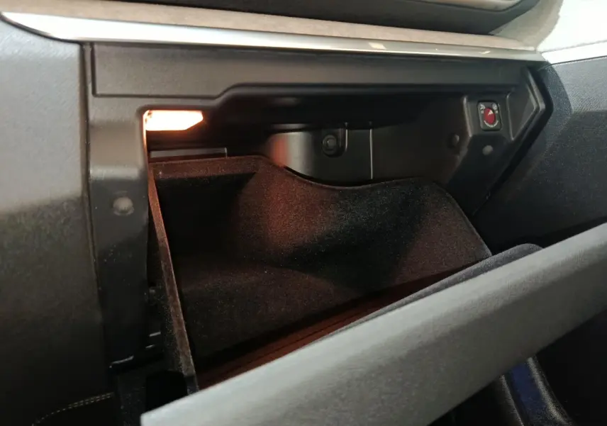Vue rapprochée de la boîte à gants ouverte du Peugeot 5008 GT 2023, intérieur noir avec éclairage intérieur.