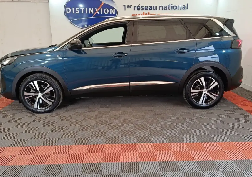 Vue de profil côté gauche d’un Peugeot 5008 GT bleu 2023 avec jantes alliage et toit noir.