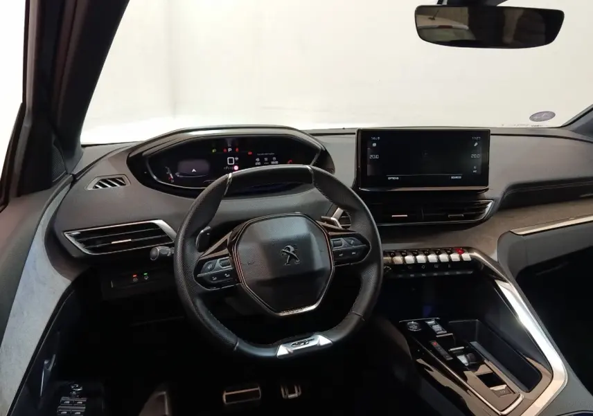 Vue intérieure du poste de conduite du Peugeot 5008 GT 2023, avec volant cuir, écran tactile central et combiné numérique.