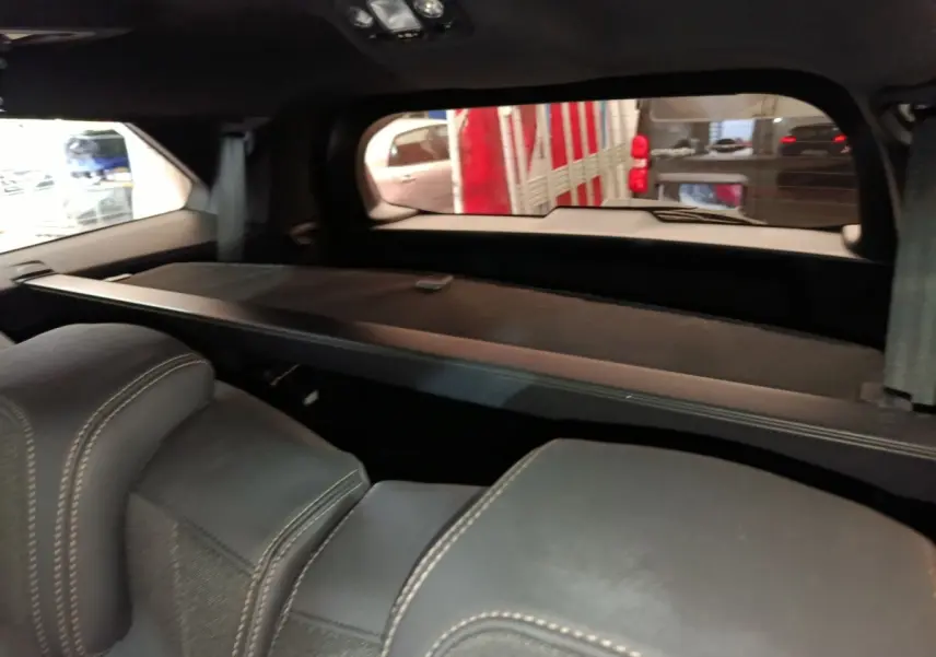 Vue intérieure arrière du Peugeot 5008 bleu 2023, montrant les sièges noirs avec surpiqûres et la tablette de coffre.