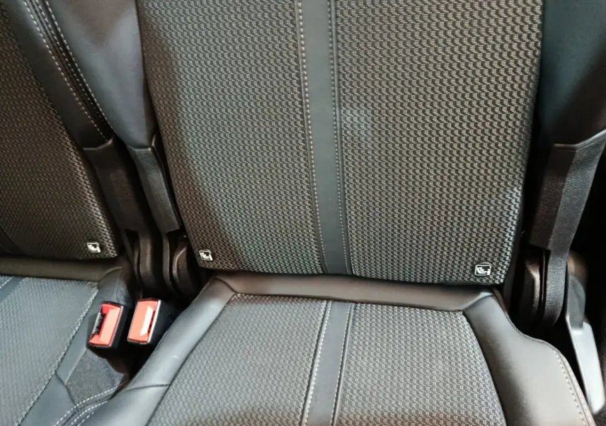 Gros plan sur les sièges arrière noirs du Peugeot 5008 2023 avec ceintures rouges et logo Isofix visible.