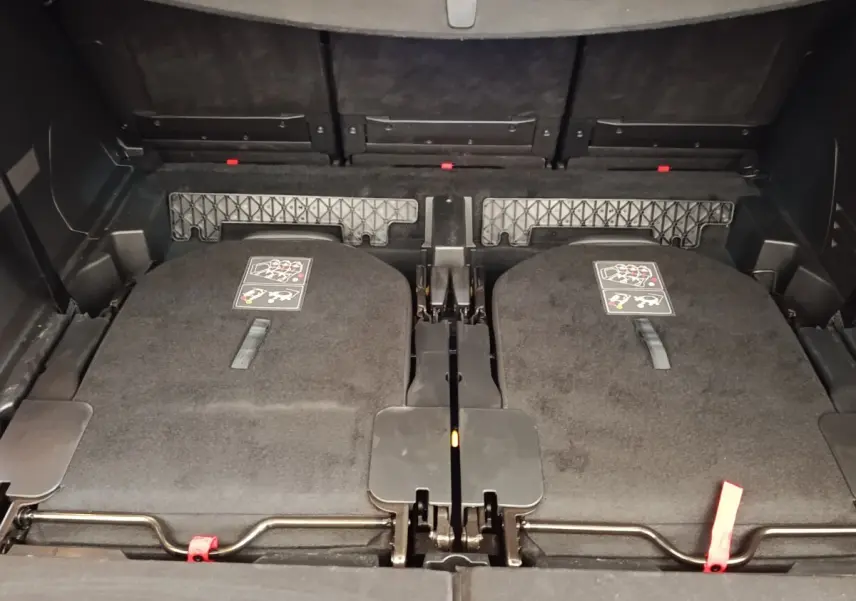 Vue rapprochée du coffre arrière du Peugeot 5008 bleu 2023 avec sièges rabattus et espace de rangement plat.