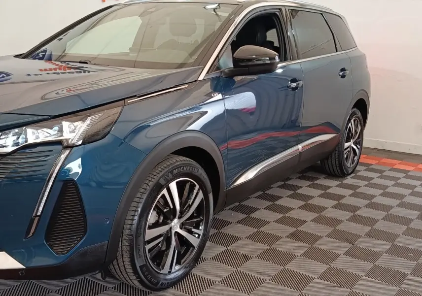 Vue 3/4 avant droit du Peugeot 5008 bleu 2023 avec jantes alliage et feux LED distinctifs.