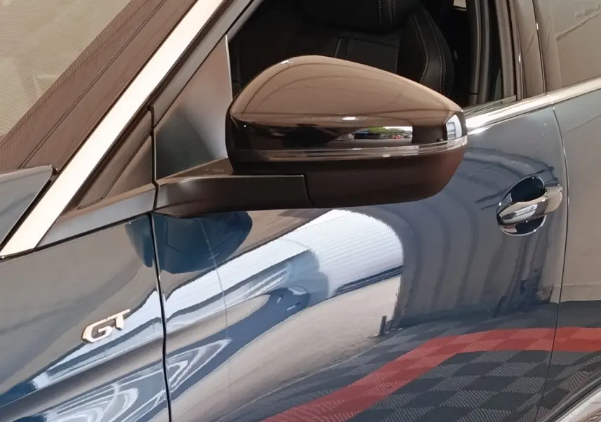 Gros plan sur la porte côté gauche d’un Peugeot 5008 GT bleu avec rétroviseur noir et badge GT visible.