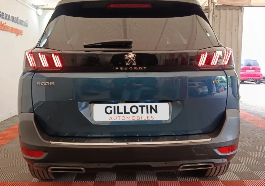 Vue arrière d’un Peugeot 5008 bleu 2023 avec feux LED distinctifs et double sortie d’échappement chromée.