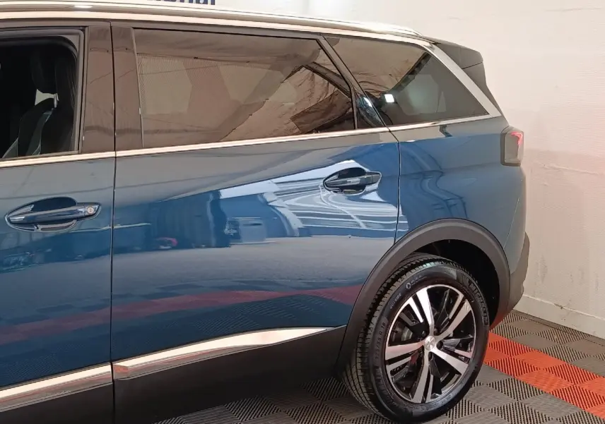 Vue côté droit arrière du Peugeot 5008 bleu 2023 avec jante alliage et vitres teintées.