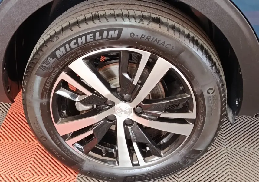Gros plan sur la jante alliage bicolore et pneu Michelin d’un Peugeot 5008 bleu, côté droit avant.