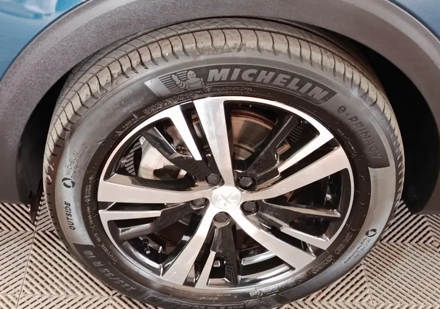 Gros plan sur la roue avant droite du Peugeot 5008 bleu, mettant en valeur la jante alliage bicolore et le pneu Michelin.