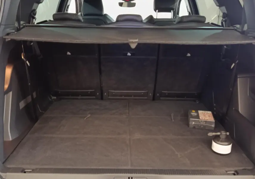 Coffre ouvert vu de l'arrière d'un Peugeot 5008 bleu, avec plancher plat et tablette de séparation noire.