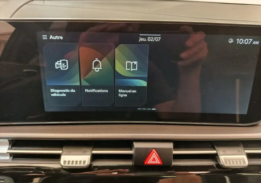 Écran tactile central affichant le menu diagnostic, notifications et manuel en ligne dans un Kia Sportage gris foncé.
