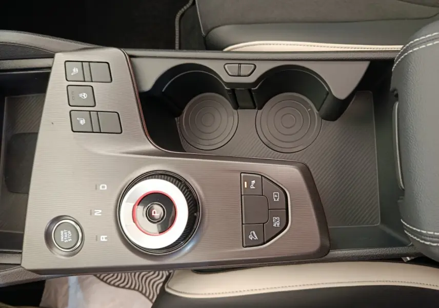 Vue en plongée du sélecteur de boîte automatique et des commandes sur la console centrale du Kia Sportage gris foncé.