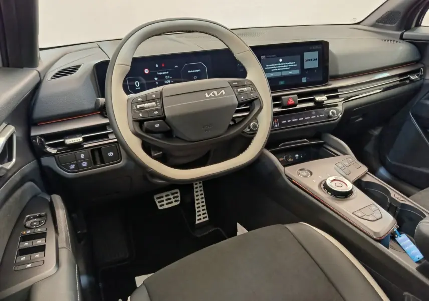 Vue intérieure côté conducteur du tableau de bord et volant bi-ton beige et noir du Kia Sportage gris foncé 2026.