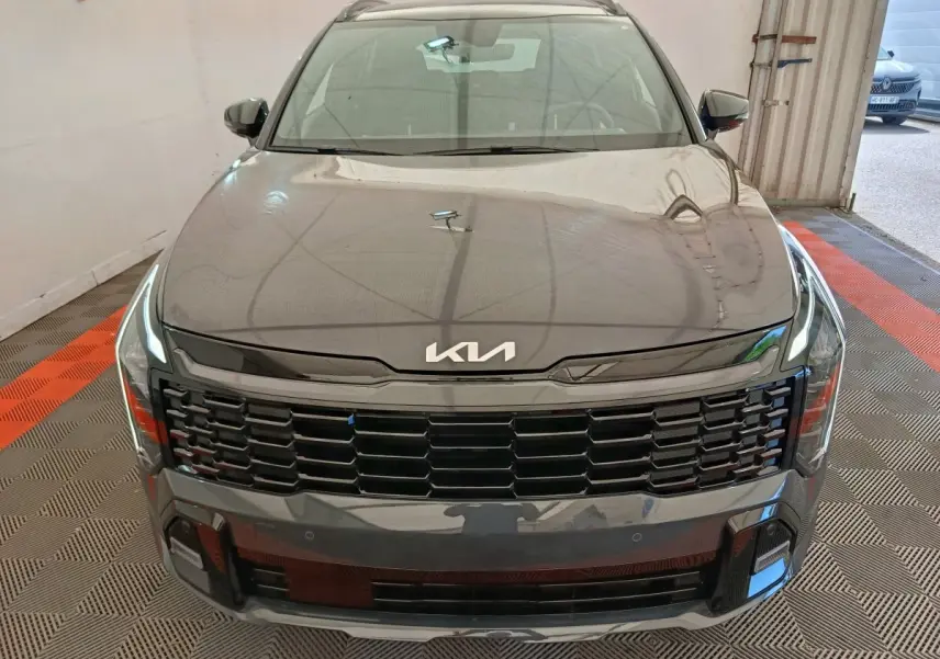 Vue avant d'un KIA Sportage gris foncé avec calandre noire et logo KIA moderne sur le capot.