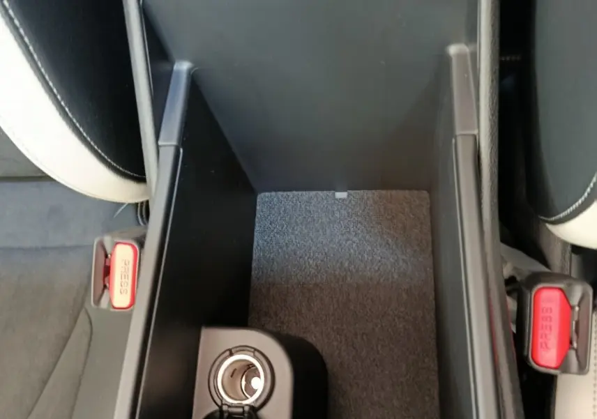 Vue plongeante sur la console centrale ouverte du Kia Sportage 2026, intérieur noir avec prise allume-cigare visible.
