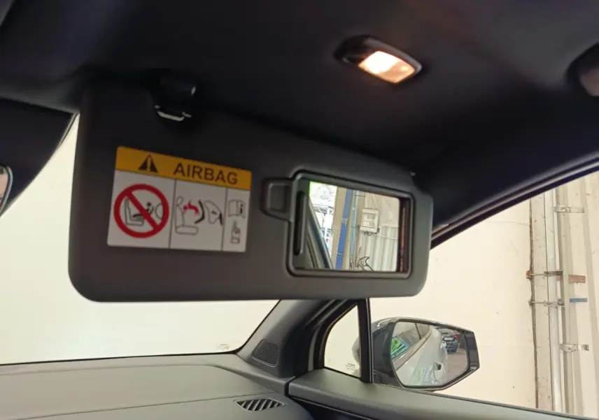 Vue intérieure du pare-soleil côté conducteur avec miroir et rétroviseur, dans un Kia Sportage gris foncé.