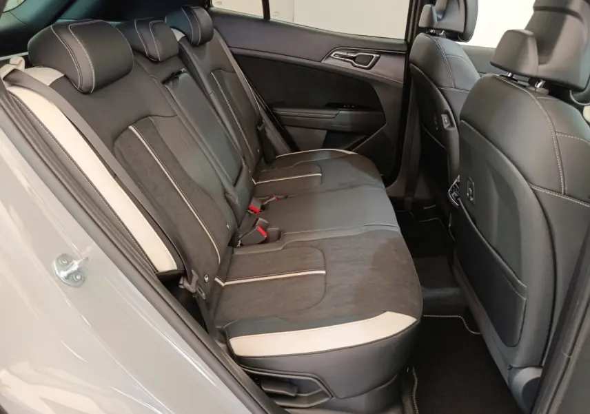Vue intérieure côté gauche des sièges arrière noirs avec surpiqûres blanches du Kia Sportage gris foncé 2026.