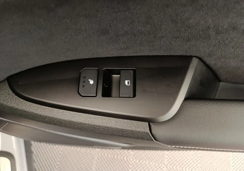 Gros plan sur les commandes de siège chauffant et de verrouillage sur la porte côté gauche du Kia Sportage gris foncé 2026.