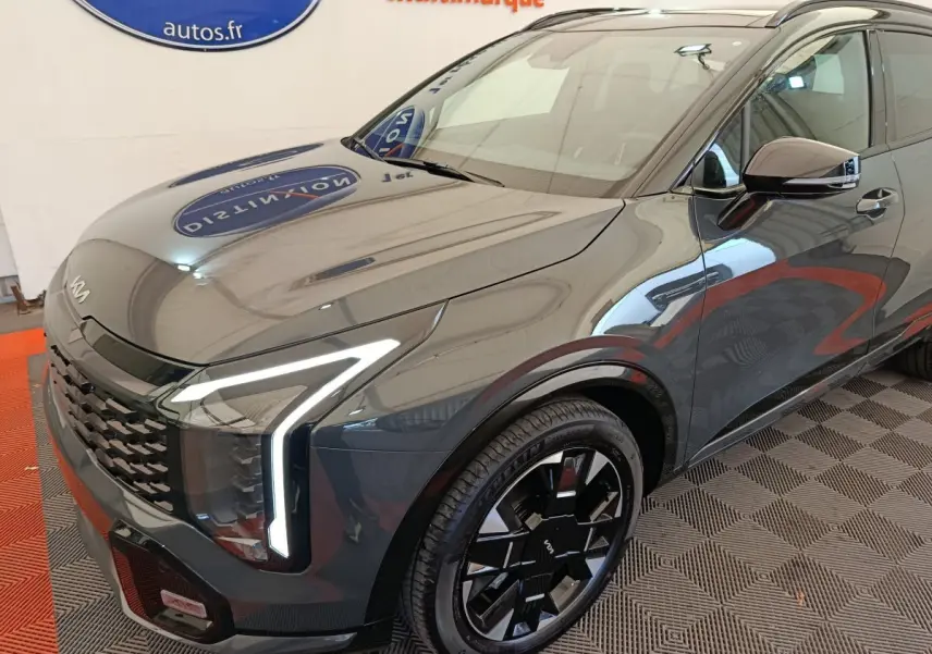 Vue 3/4 avant droit du KIA Sportage gris foncé avec phares LED en forme de L et jantes noires stylisées.