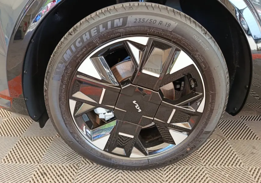 Gros plan sur la roue avant droite du KIA SPORTAGE gris foncé avec jante noire et argentée au design géométrique.