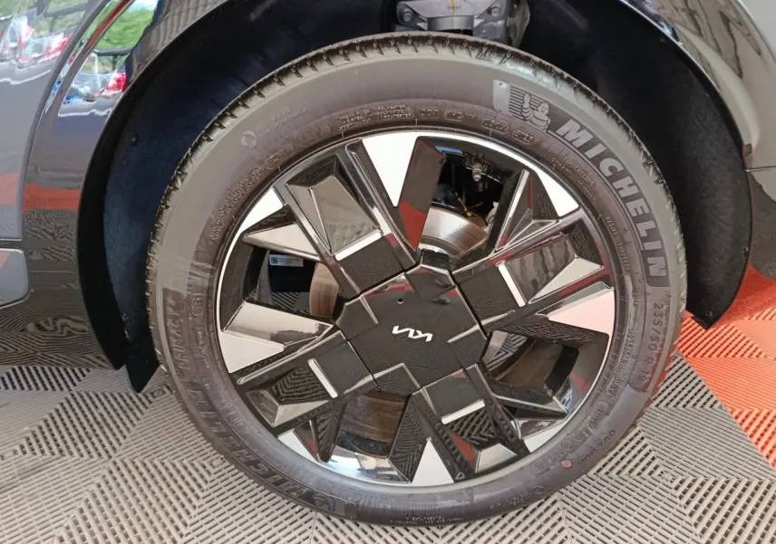 Gros plan sur la roue avant gauche gris foncé du Kia Sportage 2026 avec jante noire brillante au design géométrique.