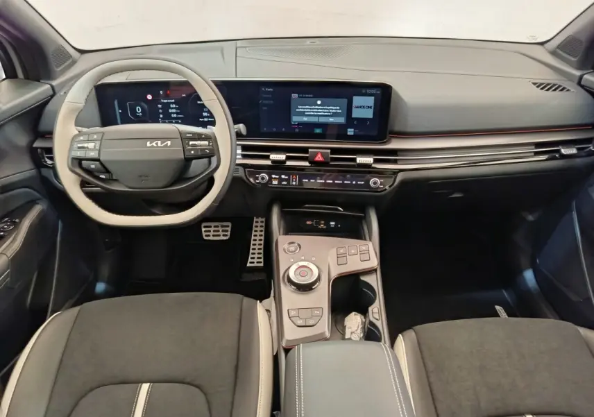 Vue intérieure avant du Kia Sportage gris foncé, tableau de bord avec écran tactile large et volant multifonctions.
