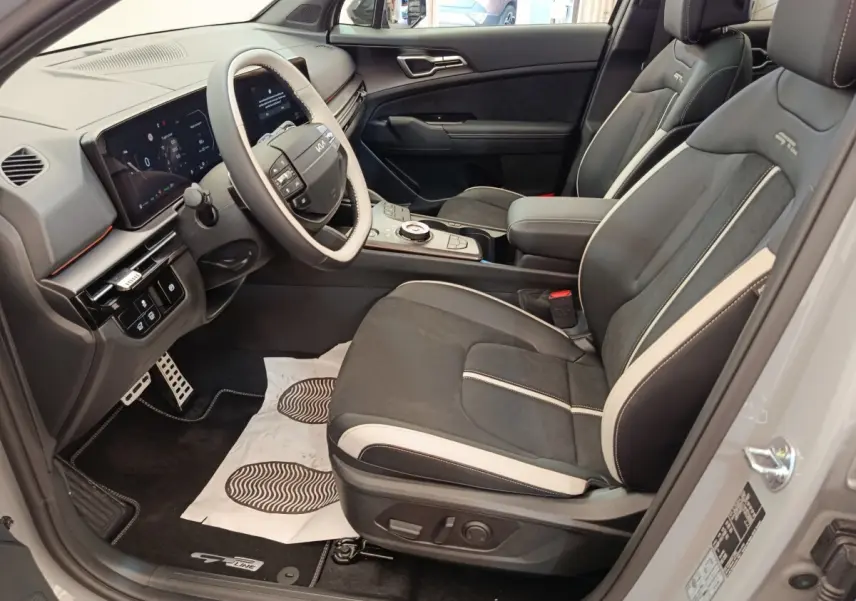 Vue intérieure côté conducteur du Kia Sportage gris foncé, avec sièges GT-Line en cuir noir et beige et tableau de bord numérique.