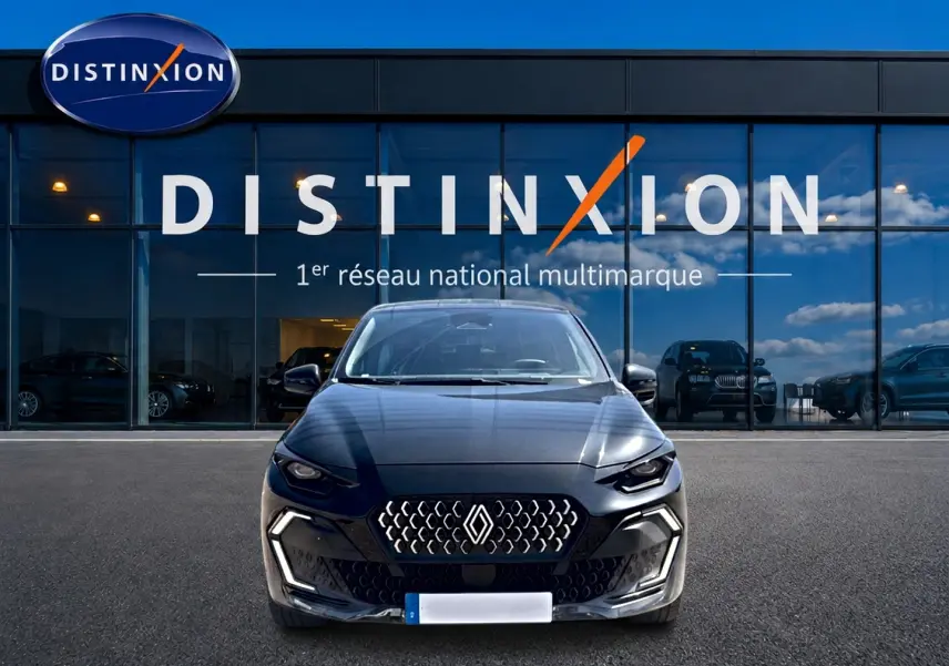 Vue frontale d'une Renault Clio VI noire garée devant une vitrine avec logo Distinxion en arrière-plan.