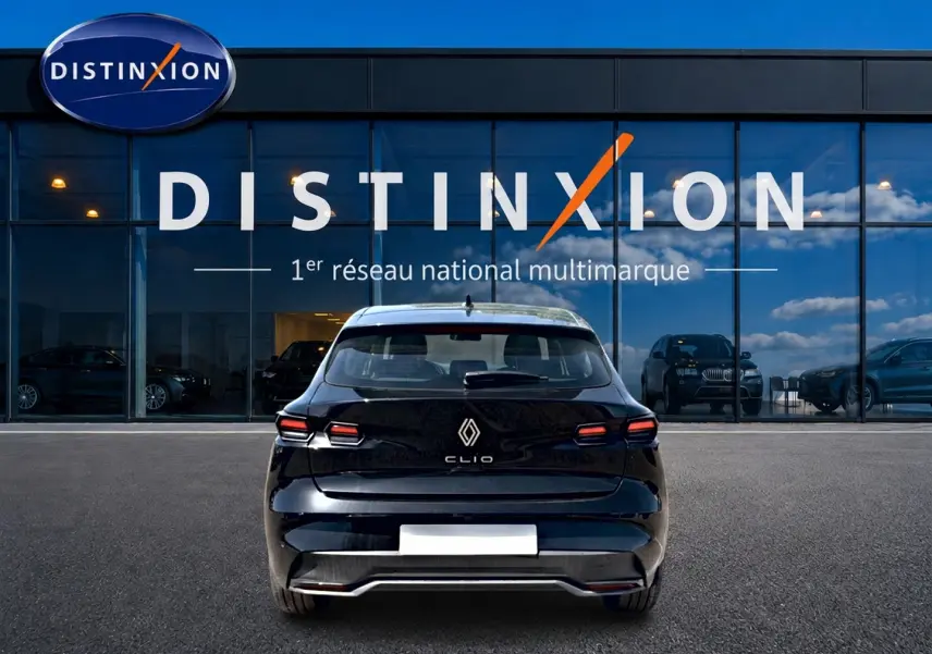 Vue arrière d'une Renault Clio VI noire garée devant une vitrine avec logo Distinxion en arrière-plan.