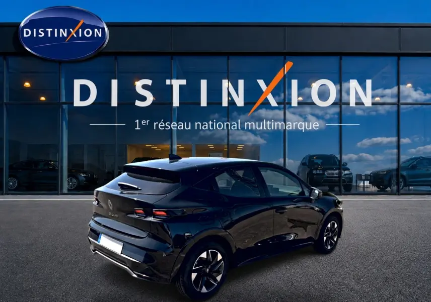 Vue 3/4 arrière droite d'une Renault Clio VI noire garée devant une vitrine avec logo Distinxion.