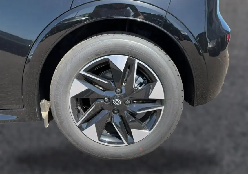 Gros plan sur la roue arrière droite noire avec jante alliage bicolore de la Renault Clio VI noire.