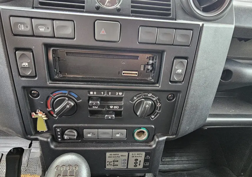 Tableau de bord noir du Land Rover Defender 90 2013, vue frontale centrée sur les commandes et levier de vitesses manuel.