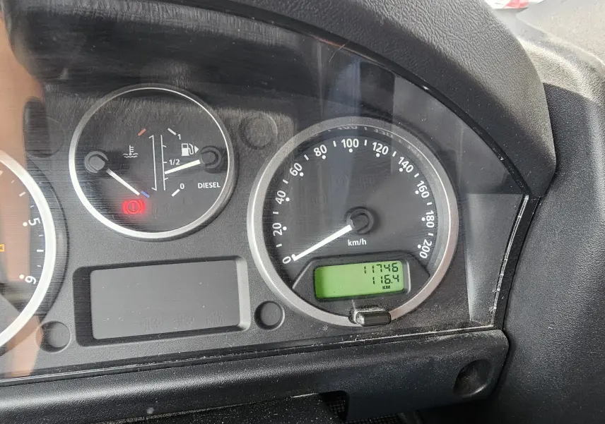 Gros plan sur le tableau de bord noir du Land Rover Defender 90 Diesel 2013, affichant compteur et témoins lumineux.