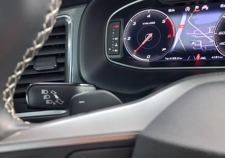 Tableau de bord numérique du SEAT Ateca 2025, affichant compte-tours et navigation, avec volant partiel en cuir noir.