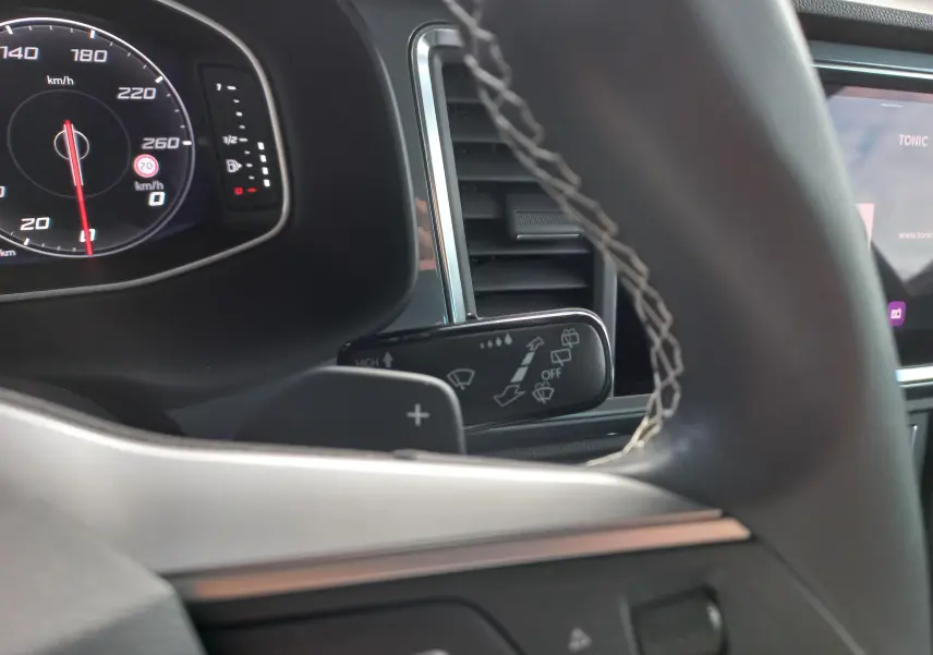 Détail intérieur sur le commodo d’essuie-glace et tableau de bord numérique du SEAT Ateca 2.0 TDI noir Magic Nacré.