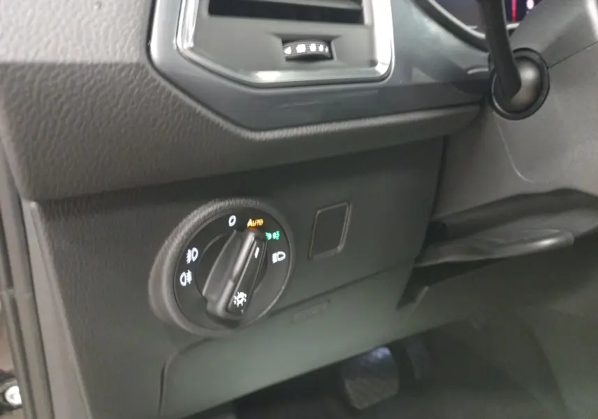 Gros plan sur le bouton de commande des phares dans l'habitacle noir du SEAT Ateca 2025 côté gauche.
