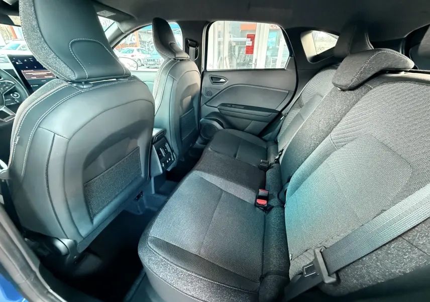 Vue intérieure arrière côté droit du Renault Captur E-Tech hybride 2025, sièges tissu gris et dossiers cuir noir.
