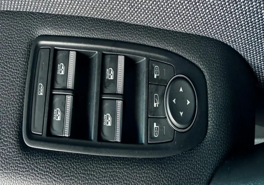 Gros plan sur les commandes des vitres et rétroviseurs côté conducteur du Renault Captur bleu Iron Metal avec toit noir 2025.