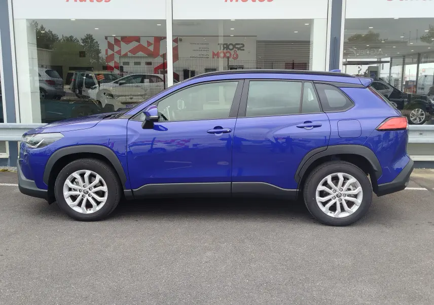 Vue de profil côté gauche d’un Toyota Corolla Cross 1.8l 140h Dynamic bleu cosmique avec jantes alliage et protections noires.