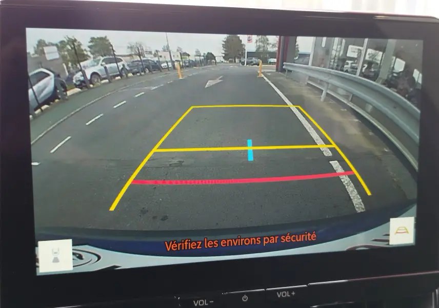 Vue de la caméra de recul de la Toyota Corolla Cross 2024, affichant les lignes de guidage sur un parking urbain.