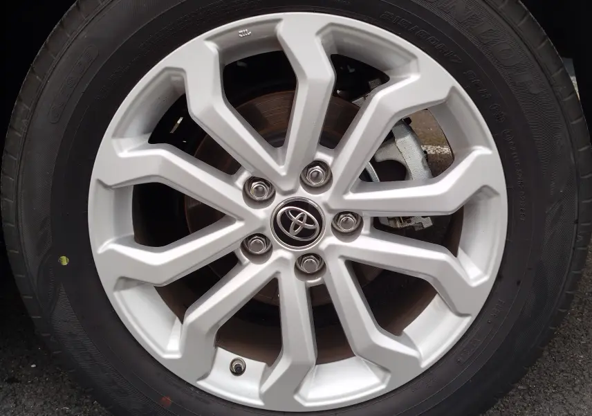 Gros plan sur la jante alliage argentée avec logo Toyota au centre du Toyota Corolla Cross 2024 Bleu Cosmique.