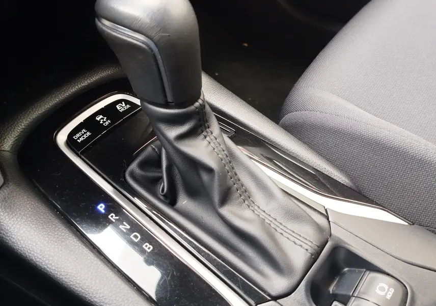 Le levier de vitesses automatique noir du Toyota Corolla Cross 1.8l 140h Dynamic, vu en gros plan côté conducteur.