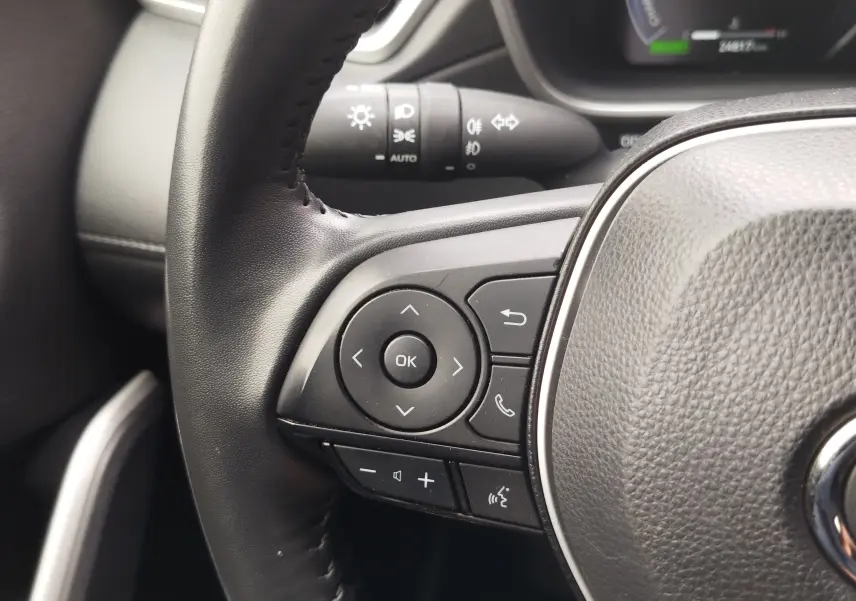 Gros plan sur les commandes multifonctions à gauche du volant en cuir noir du Toyota Corolla Cross 2024.