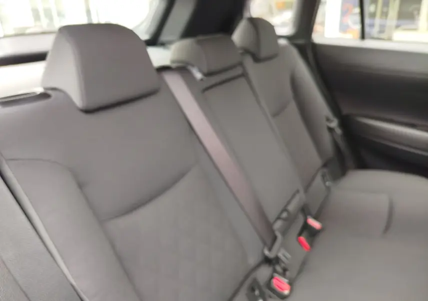 Vue intérieure des sièges arrière gris foncé de la Toyota Corolla Cross 2024, avec ceintures de sécurité visibles.